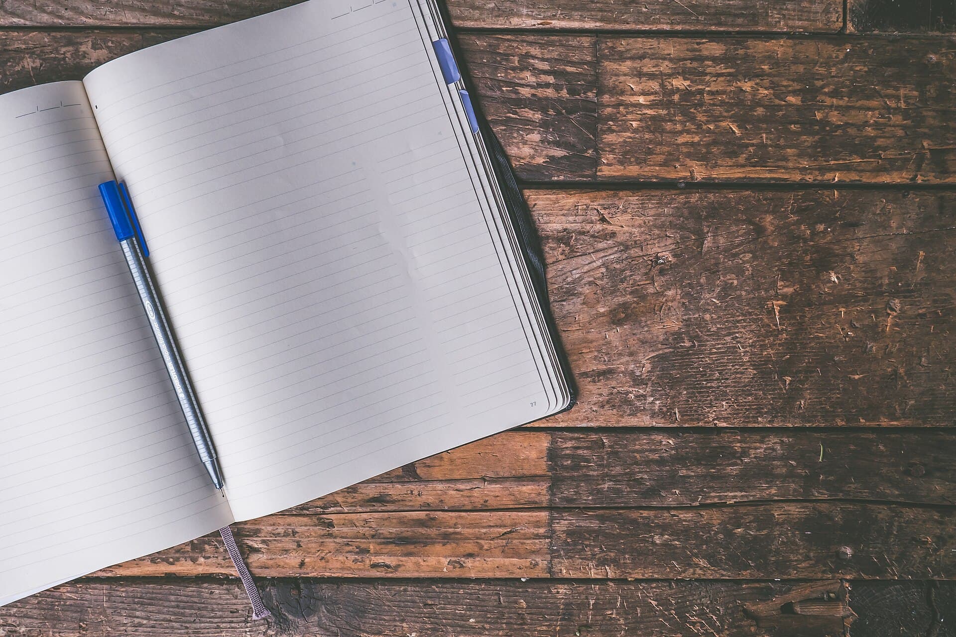 An open notebook and pen on a wooden desk